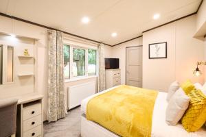 a bedroom with a yellow bed and a window at Sunbird Lodge with Hot Tub in York +38 photos