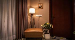 a room with a chair and a lamp and curtains at Cozy Two-Bedroom Apartment with Balcony in Islamabad