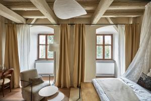 a bedroom with a bed and a chair and windows at Zámek Žďár in Žďár nad Sázavou +117 photos