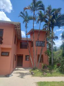 a house with palm trees in front of it at Quarto na mansão ilhabela in Ilhabela