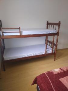 a wooden bunk bed with white sheets on it at Quarto na mansão ilhabela in Ilhabela