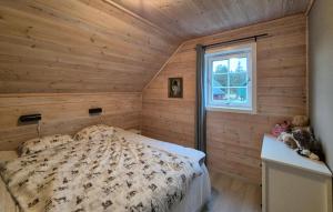 a bed in a room with wooden walls and a window at Beautiful Home In Bøvågen With Sauna in Otterholmen +22 photos