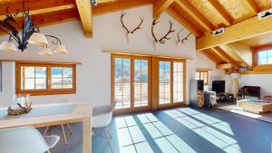 a living room with wooden ceilings and a dining table and chairs at Abitaziun Allegra Sur DG - Zuoz in Zuoz