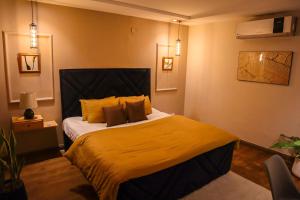 a bedroom with a large bed with yellow sheets and pillows at Cozy Two-Bedroom Apartment with Balcony in Islamabad