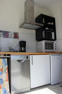 une cuisine avec un comptoir avec un micro-ondes et une cuisinière dans l'établissement L'HERMINE - pour 2 personnes, proche de la plage, à Binic