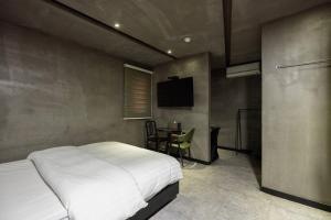 a bedroom with a bed and a table and a television at XYM Hotel Icheon in Icheon