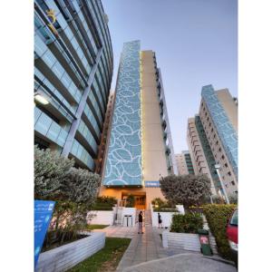 kobieta stoi przed dwoma wysokimi budynkami w obiekcie Stylish 1BR Retreat Al Sana, Al Raha Beach w Abu Zabi