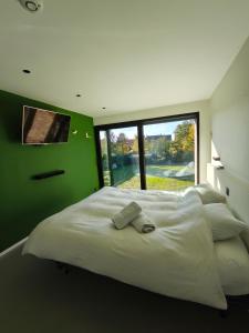 een slaapkamer met een groot wit bed en een groene muur bij Modern spatious house near Bruges in Brugge