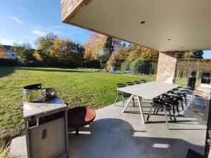 een patio met een tafel en stoelen en een veld bij Modern spatious house near Bruges in Brugge