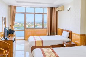 a hotel room with two beds and a window at Viet Thai Hotel in Hồng Lĩnh