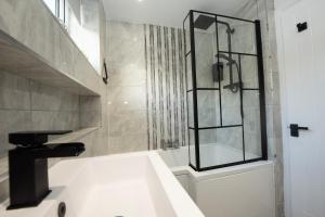 a bathroom with a sink and a glass shower at Stylish 4 Bed House, Free Parking, Close to M4 Newport in Newport +26 photos