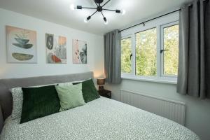 a bedroom with a bed with green pillows and windows at Stylish 4 Bed House, Free Parking, Close to M4 Newport in Newport