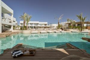 a large swimming pool with chairs and a building at Aya Resort - Adults Only in Ayia Napa