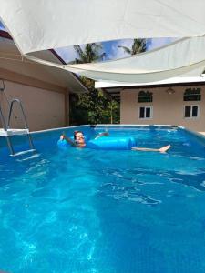 a young boy is swimming in a swimming pool at Villa Skanderbeg Guest House Talaudyong Beach in Bacungan