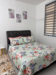 a bed with a floral comforter in a bedroom at Coach homestay in Kuantan