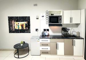 a kitchen with white cabinets and a microwave at WinHaven Guest House in Randfontein