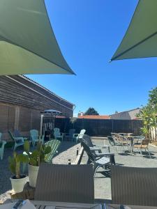 a patio with chairs and tables and umbrellas at Happy Break in Saint-Michel-en-lʼHerm