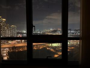 einen Blick auf die Stadt von einem Fenster in der Nacht in der Unterkunft Shine Stay 5 Min from Songdo Moonlit Festiv Park Station in Taeam