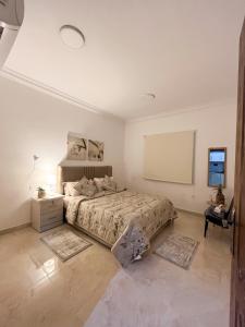 a white bedroom with a bed and a tv at شقق راقية بأثاث حديث وراقي 1 in Dammam