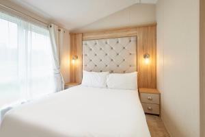 ein Schlafzimmer mit einem weißen Bett und einem Fenster in der Unterkunft The Flamingo Lodge with Hot Tub in York