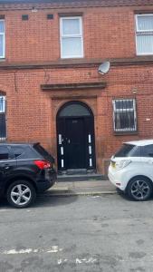 two cars parked in front of a brick building at Majesty Suite in Manchester