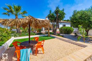 a patio with a table and chairs under a straw umbrella at Villa Alamito by Abahana Villas in Balcon del Mar