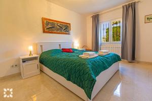a bedroom with a bed with a green comforter and a window at Villa Alamito by Abahana Villas in Balcon del Mar +14 photos