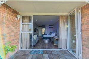 Una sala de estar con una puerta corrediza de vidrio y un dormitorio. en Brookes at Sea, en Gqeberha