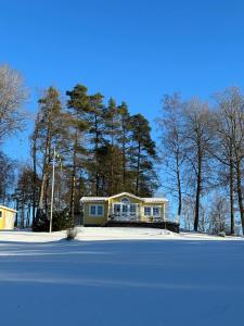 a house in the middle of a snow covered yard at Stunning lakeside home with sauna surrounded by nature in Sandared