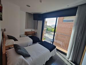 a hotel room with two beds and a large window at Hostal Manel in Pineda de Mar +81 photos