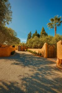 a driveway with a gate and a fence and a palm tree at EdenAtlas Chambres d'hôtes - Amizmiz in Amizmiz