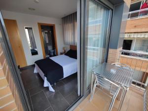 a bedroom with a bed and a balcony with a table at Hostal Manel in Pineda de Mar