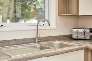 un comptoir de cuisine avec un évier et une fenêtre dans l'établissement Reynards Retreat Lodge with Hot Tub, à Barmby on the Moor 31 autres photos