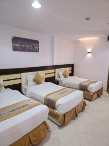 a hotel room with three beds in a room at برج الجوار السكني أجياد المصافي Jiwar Tower Ajyad Al Masafi in Al Gharīth +4 photos