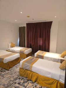 a hotel room with three beds in a room at برج الجوار السكني أجياد المصافي Jiwar Tower Ajyad Al Masafi in Al Gharīth