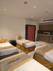 a hotel room with three beds and a kitchen at برج الجوار السكني أجياد المصافي Jiwar Tower Ajyad Al Masafi in Al Gharīth
