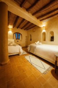 a bedroom with two beds and a table in it at EdenAtlas Chambres d'hôtes - Amizmiz in Amizmiz
