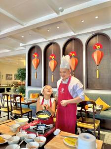 Un hombre y una mujer cocinando en un restaurante en Little Residence - A Boutique Hotel & Spa, en Hoi An