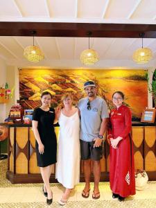 un grupo de personas de pie delante de una pintura en Little Residence - A Boutique Hotel & Spa, en Hoi An