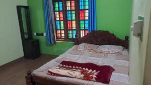 a bed in a bedroom with stained glass windows at Aura Eco Friendly Resort in Sultan Bathery