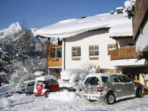 dos autos estacionados en la nieve frente a una casa en Ruhige Wohnung Im Ortszentrum, en Sankt Gallenkirch