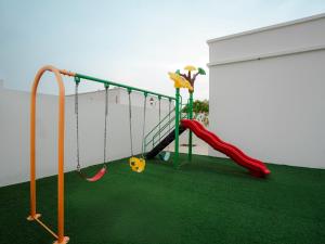 a playground with a slide and swings at Al-Salam Villa-Family Pool & Private Garden in Misfāh