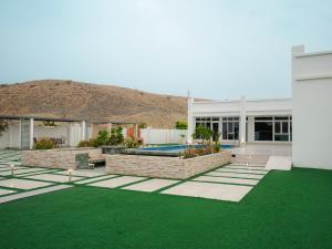 a house with a yard with green grass at Al-Salam Villa-Family Pool & Private Garden in Misfāh