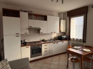 a kitchen with white cabinets and a table and a dining room at OTB Italia 6 - Rifugio moderno tra Venezia e Treviso con 2 terrazze e Parcheggio coperto in Preganziol