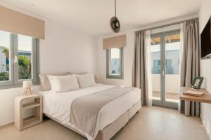 a white bedroom with a large bed and windows at La Maltese Central in Naousa