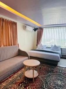 Una habitación de hotel con una cama, un sofá y una mesa. en NR Hotel, en Rīngas