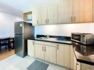 Sampongcorner 1BR unit with city view Avant at The Fort的厨房配有木制橱柜和不锈钢冰箱 更多50张照片