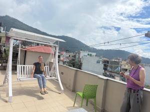 a woman sitting on a balcony with a woman taking a picture at My Stay Nepal in Kathmandu