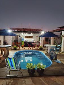 a swimming pool with chairs and a table and umbrellas at Pousada Villa Zarah in São Miguel do Gostoso