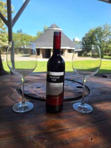 eine Flasche Wein und zwei Gläser auf einem Holztisch in der Unterkunft Kiserian cottage with gazebo garden grill - 2343 in Kiserian